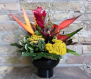 Colorful flower arrangement against brick wall.