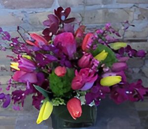 Colorful floral arrangement against brick wall.