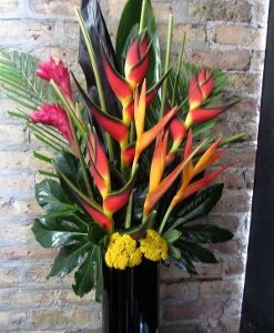 Tropical floral arrangement against brick wall.