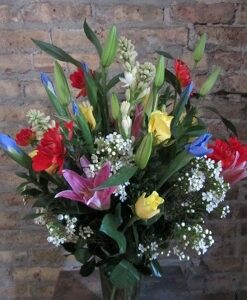 Colorful flower bouquet against brick wall.