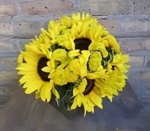 Yellow sunflowers in a bouquet against bricks.